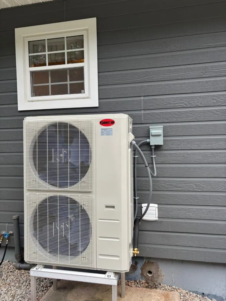 Multi-zone heat pump outdoor unit installed on a stand beside a grey-sided Nova Scotia home